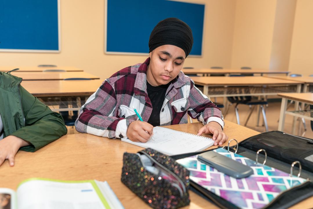 A middle school student working through a problem at a desk